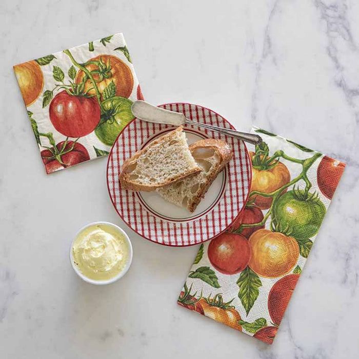 A plate with two slices of rustic bread and a butter knife sits on marble, next to a bowl of butter and a pack of 20 colorful Hester & Cook Tomato Cocktail Napkins.