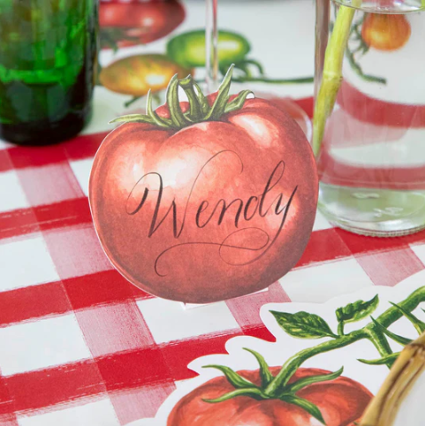 A Tomato Place Card by Hester & Cook with "Wendy" in script sits on a red-and-white checkered tablecloth, surrounded by more Tomato Place Card - Pack of 12, buffet labels, and glass jars for a charming display.