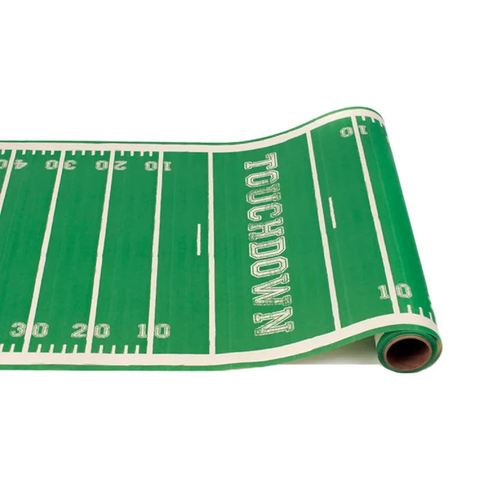 The Hester & Cook Touchdown Runner - 20x25" is a green and white paper table runner styled like a football field, complete with yard lines, numbers, and TOUCHDOWN in the end zone—ideal for parties or gift wrapping.