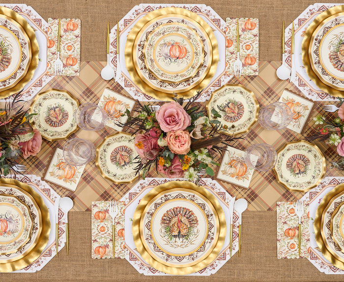 A festive table with floral centerpieces, plaid placemats, and fall napkins features Sophistiplate’s Turkey & Gourds Dinner Plates/8pk, creating a warm Thanksgiving or autumn atmosphere.