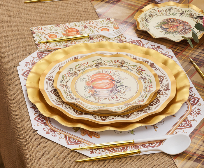 A festive autumn table features Sophistiplate’s Turkey & Gourds Salad Plates (8pk), gold cutlery, a white spoon, patterned napkins, and a plaid burlap tablecloth—perfect for your Thanksgiving celebration.