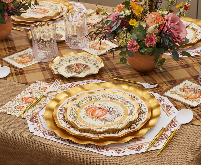 A festive table features Sophistiplate Turkey & Gourds Salad Plates (8pk), gold cutlery, crystal glasses, floral napkins, and autumn centerpieces atop a plaid and burlap tablecloth.