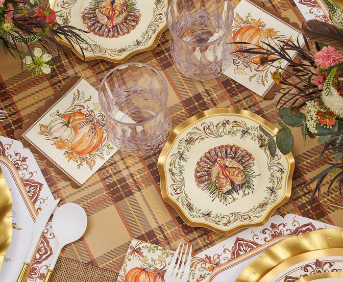 The Turkey & Gourds Table Setting Bundle by Sophistiplate LLC showcases Thanksgiving style with designer disposable plates adorned with turkey motifs, pumpkin-themed napkins, clear glasses, gold-trimmed utensils, and autumn floral centerpieces atop a plaid tablecloth.