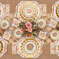 Create a festive autumn table with the Turkey & Gourds Table Setting Bundle from Sophistiplate LLC, featuring designer disposable plates adorned with turkeys and pumpkins, gold chargers, a floral centerpiece of pink roses, a plaid tablecloth, coordinated gold utensils, and glasses—all beautifully arranged for your seasonal celebration.