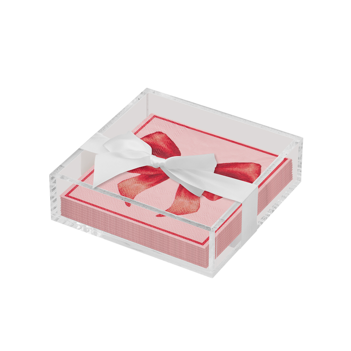 The Sophistiplate Valentines Day Cocktail Napkin with Napkin Tray features pink napkins with a red bow design in a clear acrylic tray, finished with a white ribbon—perfect for adding elegance to your modern tabletop.