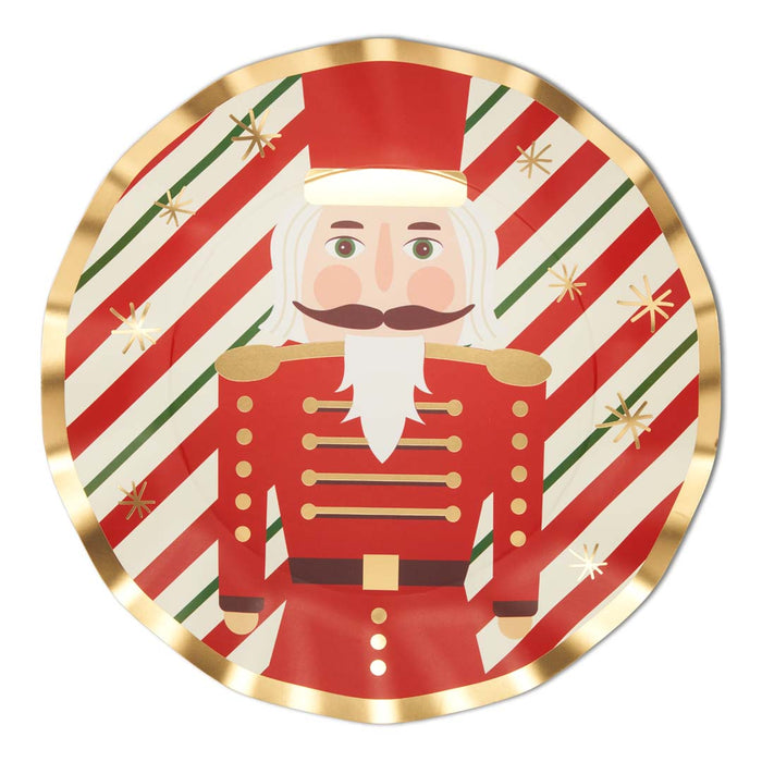 The Sophistiplate Wavy Dinner Plate Nutcracker Christmas (8/pkg) features a red and gold nutcracker on a festive striped background with gold star accents—ideal for holiday parties.