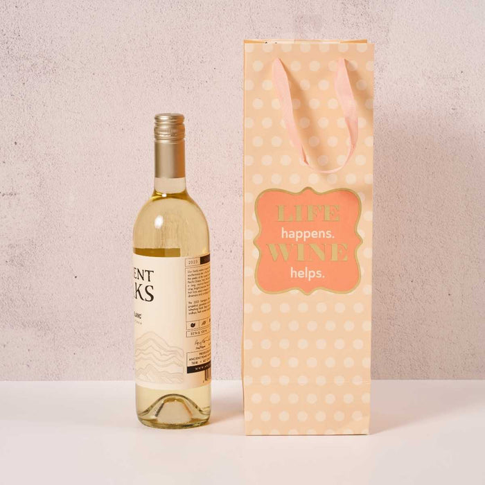 The Drinks On Me Wine Helps- Wine Bag is a peach polka dot gift bag with pink handles and a "LIFE happens. WINE helps." label—perfect for hostess gifts!.