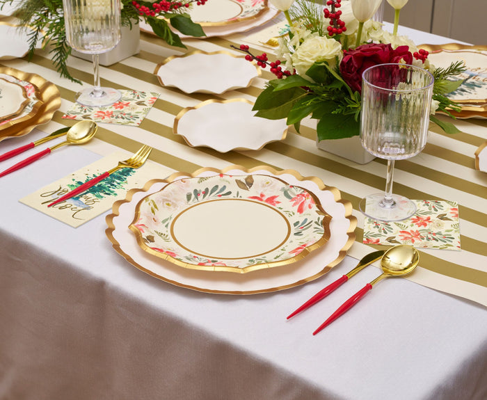 A festive holiday table is set with floral plates, red and gold utensils, crystal glasses, and the Hester & Cook Gold Classic Stripe Runner (20x25") beneath a centerpiece of red and white flowers accented with greenery and berries.