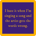 Yellow text on a blue background reads: I hate it when I’m singing a song and the artist gets the words wrong. The Drinks On Me Words Wrong Coaster, featuring a thick yellow border, makes a fun housewarming gift.
