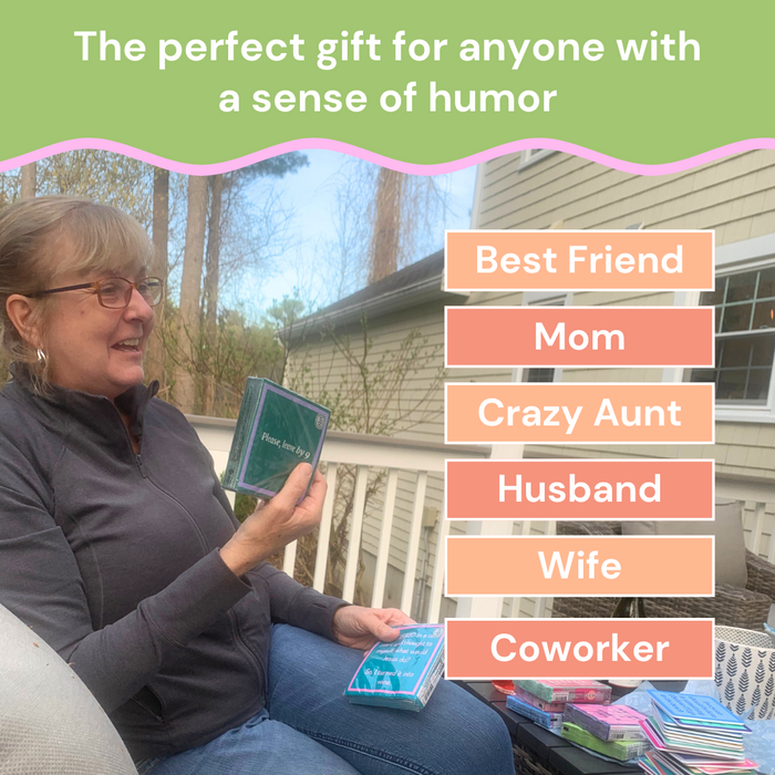 A smiling woman sits outdoors holding a "Piss off teenager" Napkin gift box by Drinks On Me. Text above reads, The perfect gift for anyone with a sense of humor: Best Friend, Mom, Crazy Aunt, Husband, Wife, Coworker.