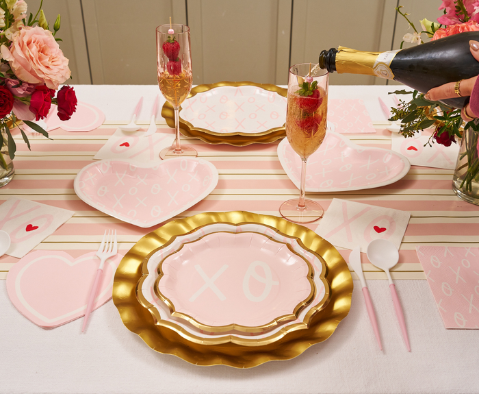 A festive table set with Sugarplum XOXO Salad Plates (8pk), heart-shaped napkins, floral centerpieces, and champagne flutes celebrates in style with playful XO and heart motifs.